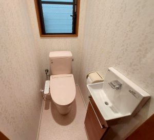 ピンクのトイレと相性の良いブラウンをキャビネット扉カラーと窓枠カラーに